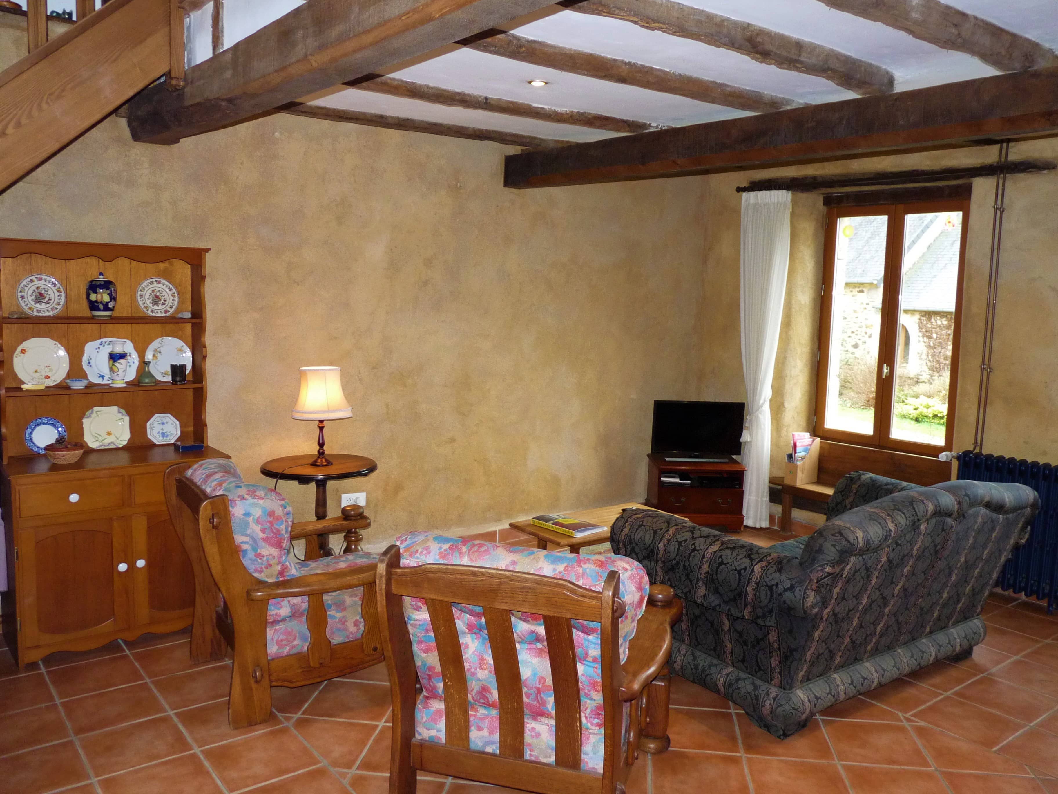 Comfortable living room of La Julerie cottage in Brittany, France, with a view of the surrounding nature and equipped with modern furniture. Ideal for relaxing after a day of sightseeing in Brittany.