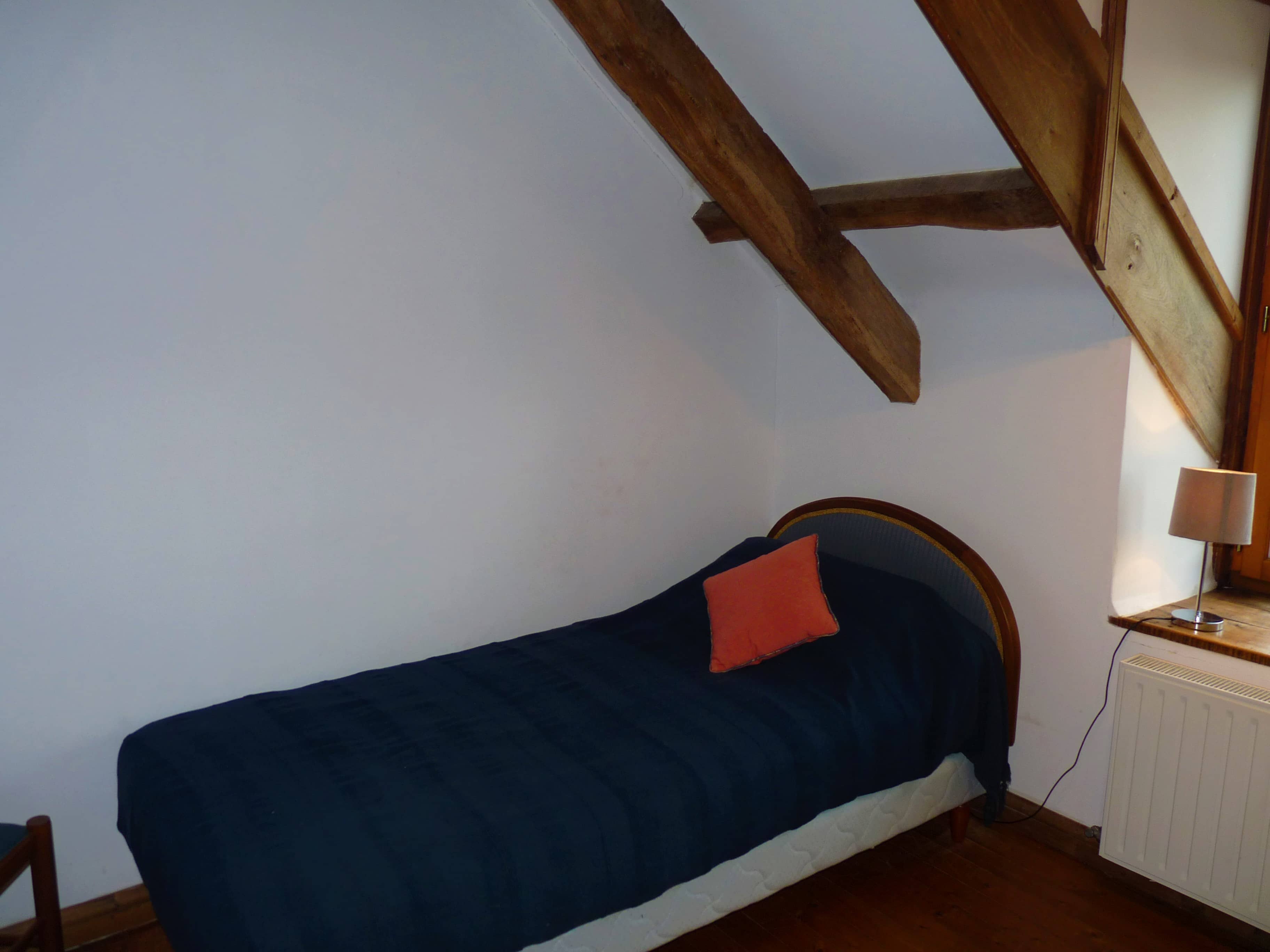 Spacious and comfortable bedroom of La Julerie cottage in Brittany, France, with a king-size bed, elegant rustic decor, a stone fireplace, and a panoramic view of the surrounding countryside. Perfect for a peaceful night's sleep after a day of sightseeing in the Brittany region.